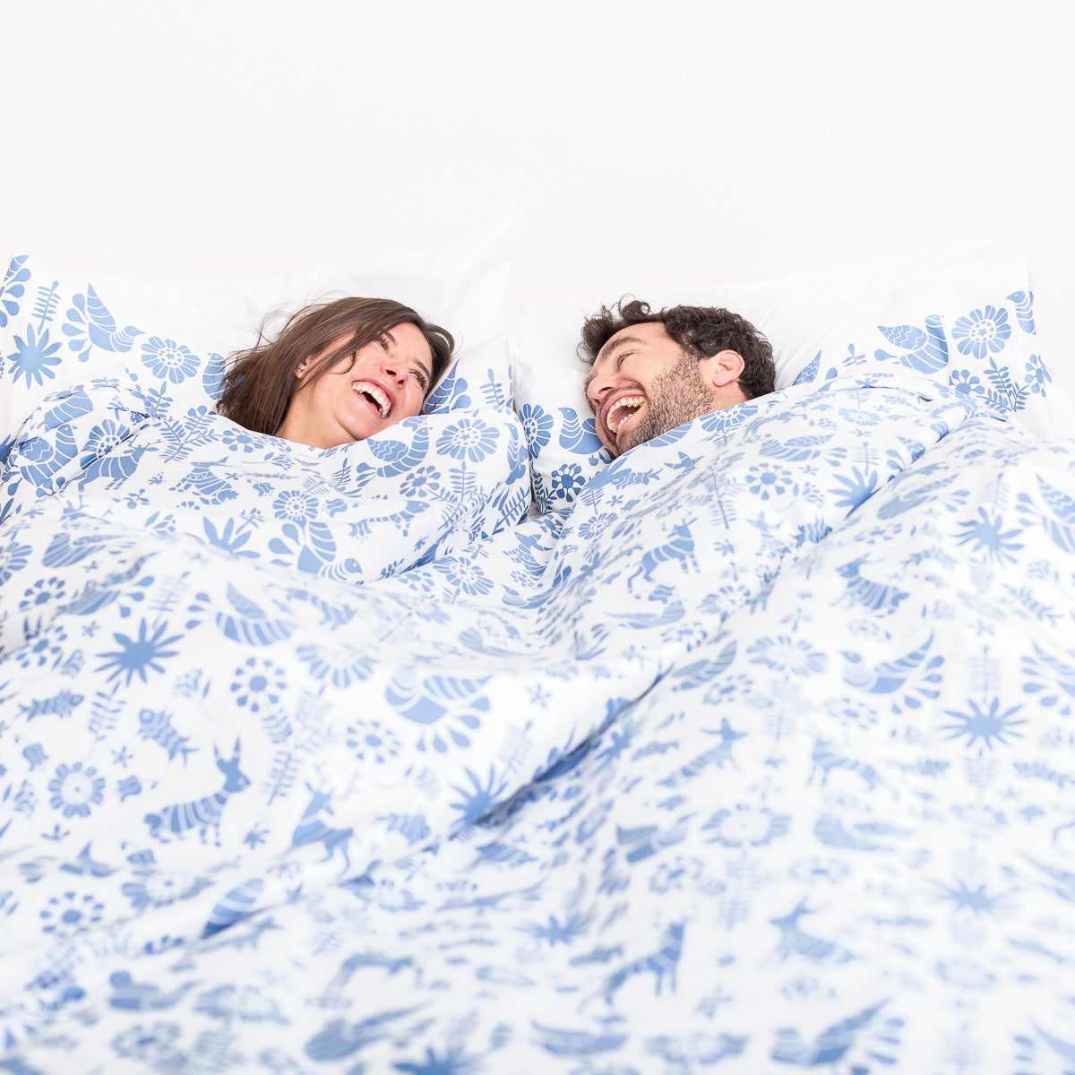 pareja en cama con sabanas y funda de duvet de algodon en animalitos azul nuit